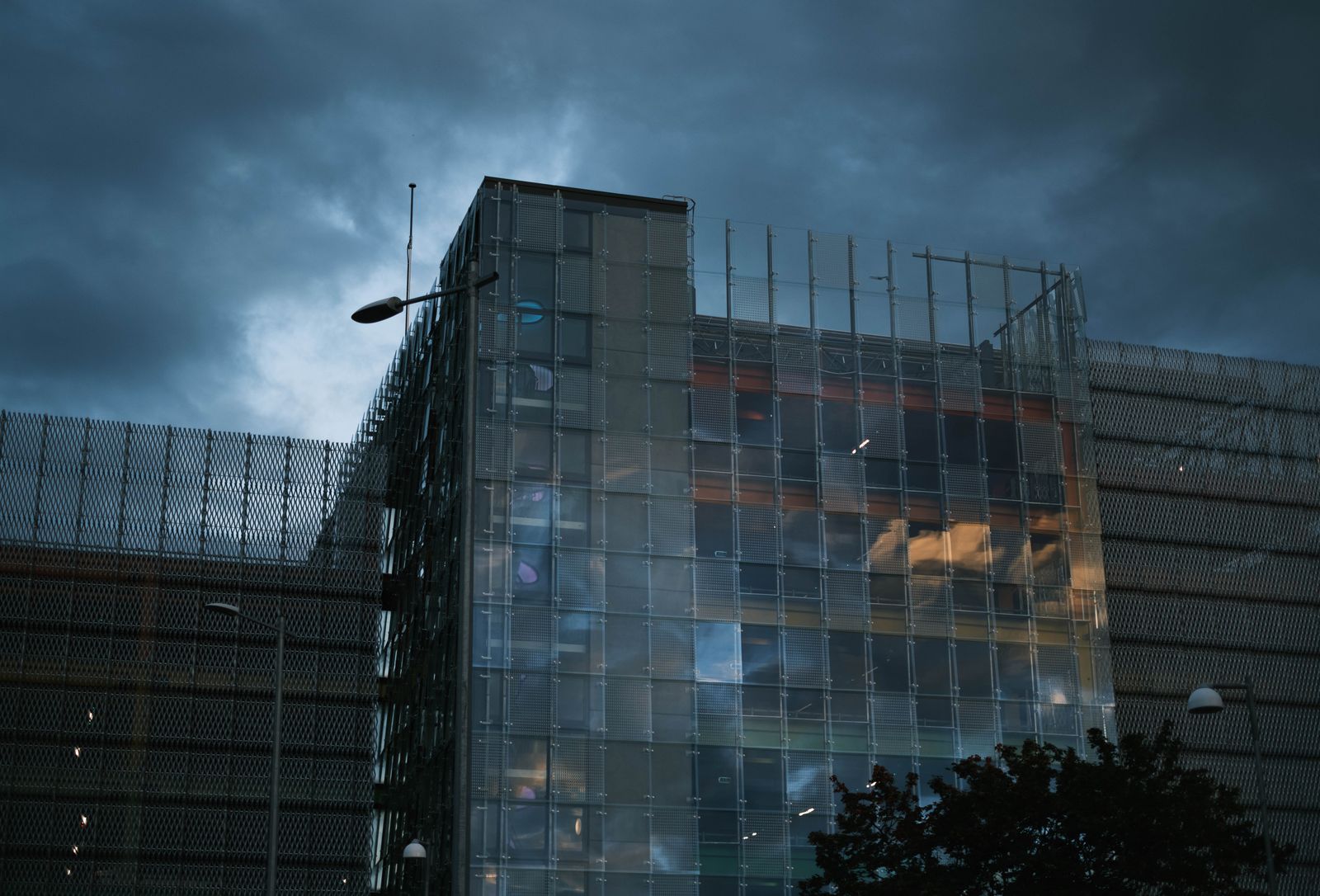 A striking image of a modern glass building under a dramatic stormy sky.